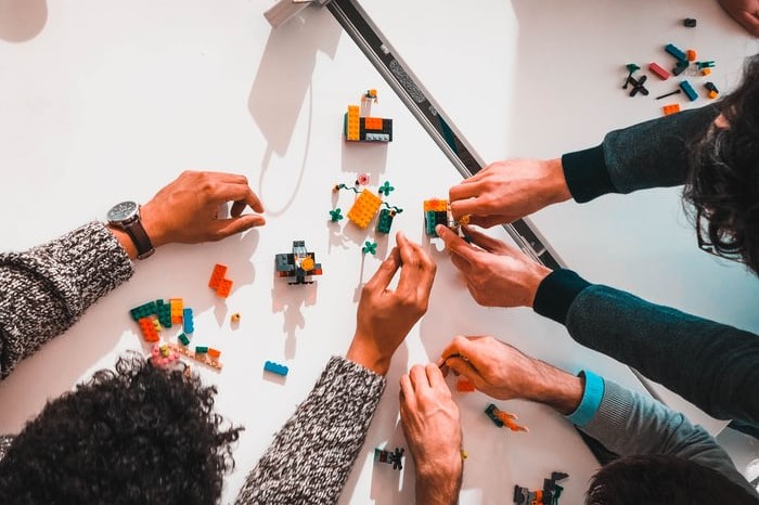 3 people creating structure with lego