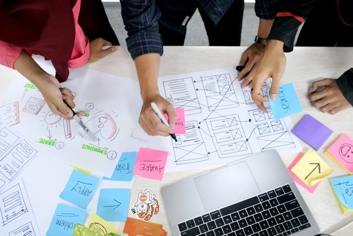 Hands of people designing an app on papers.