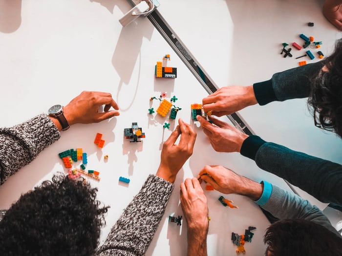 3 people creating structure with lego.