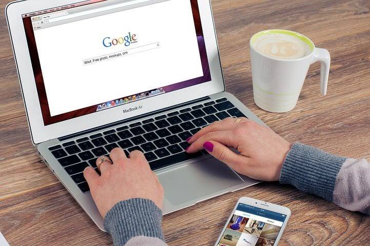 Hands of a lady shown searching on google on a macbook