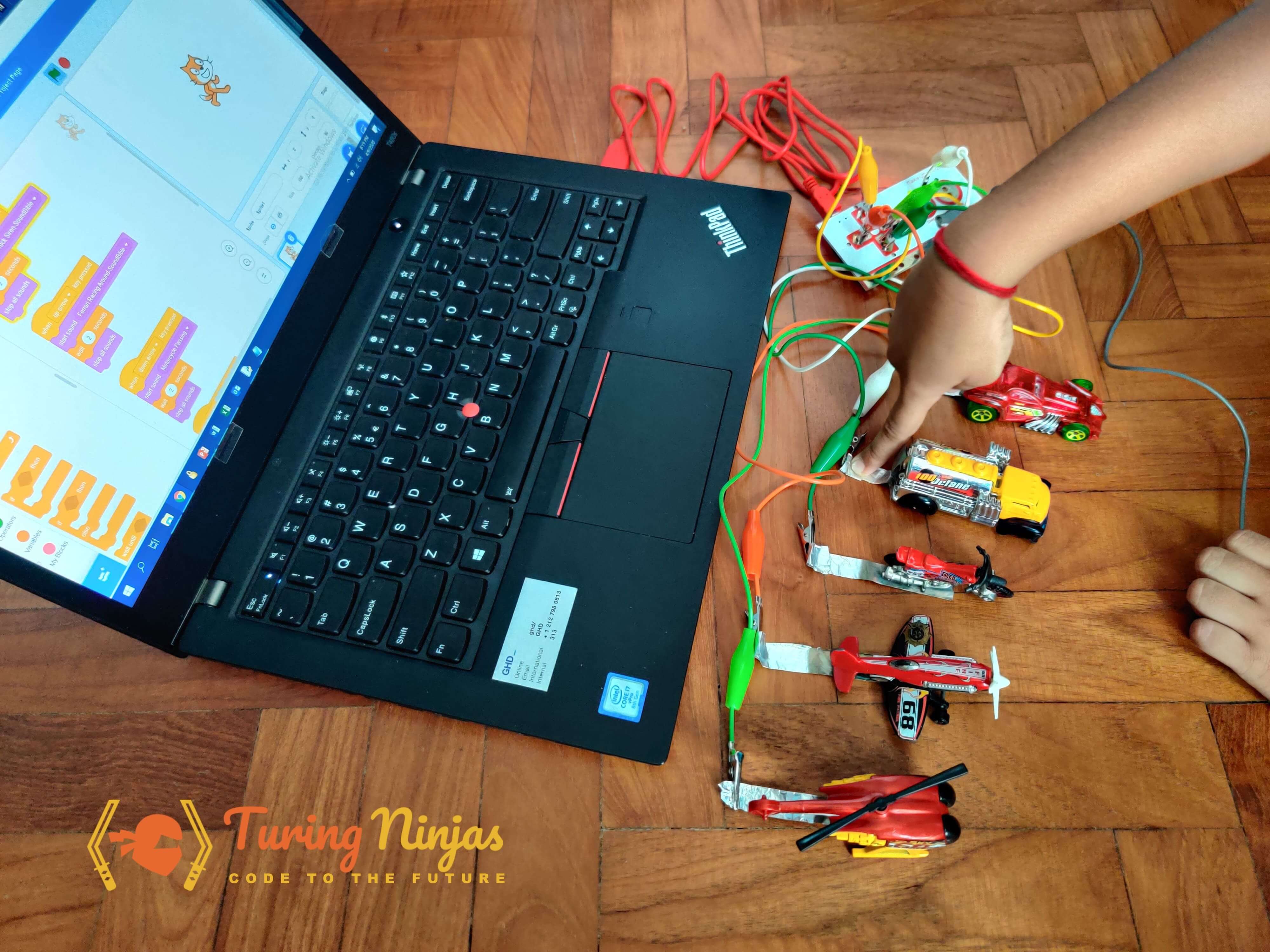 A kid adding sound effects to hotwheels using Scratch and makey makey
