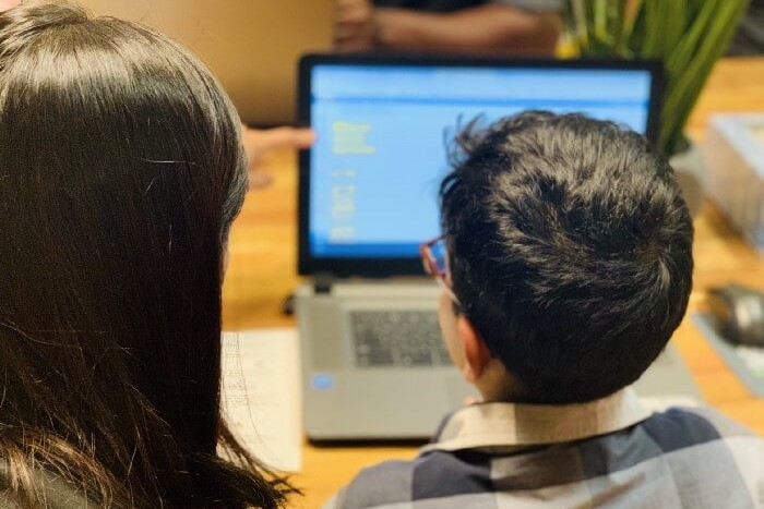 An educator teaching coding to a child on a laptop