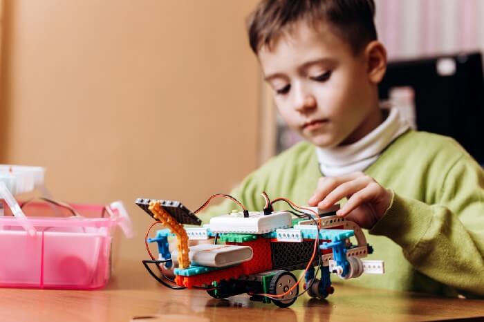 A child focusing on building a lego robot from scratch