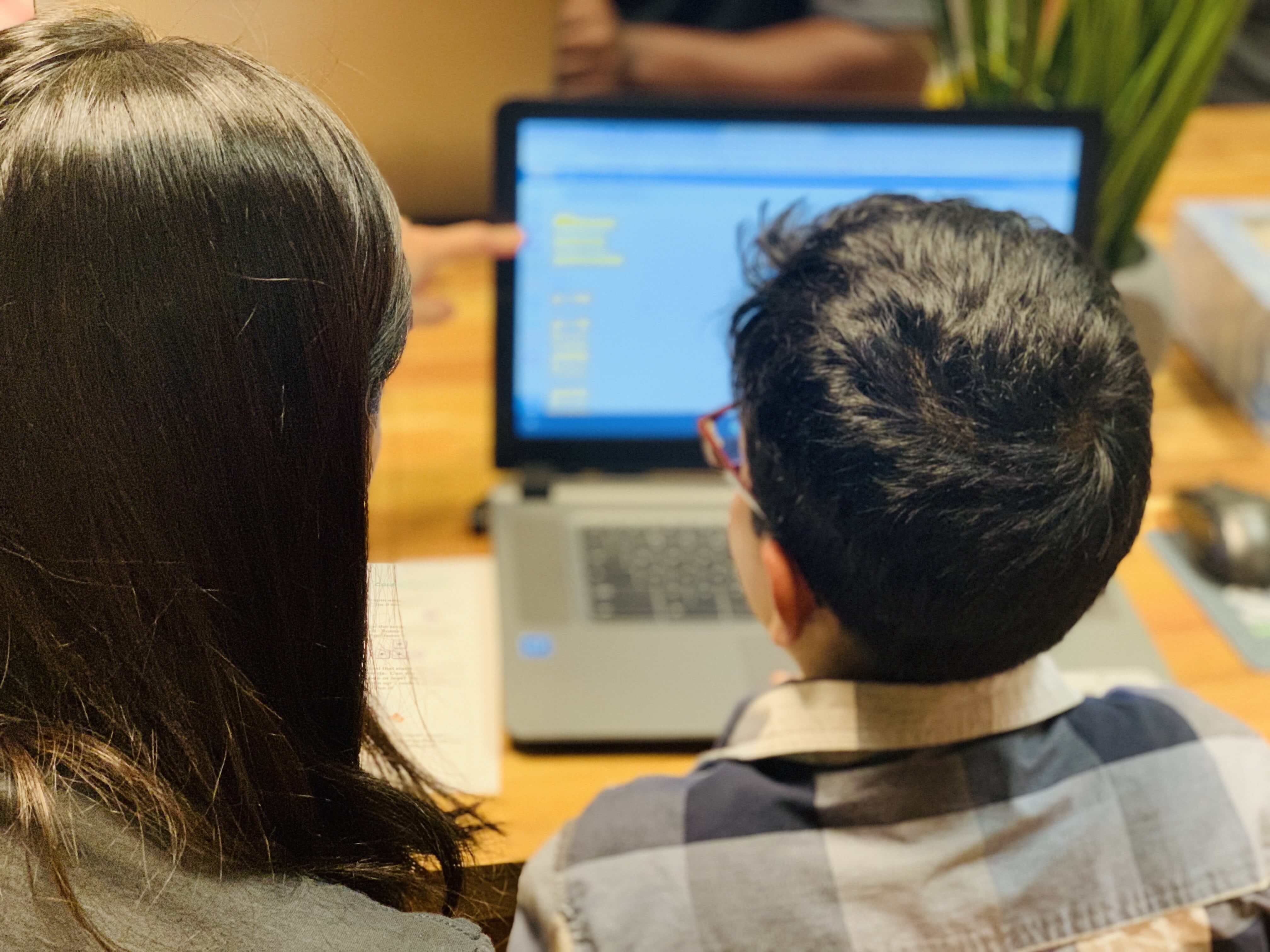 An educator teaching coding to a child on a laptop