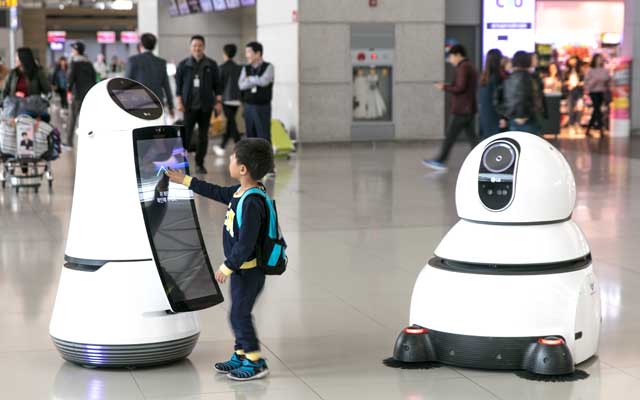 A kid playing with two robots in an airport