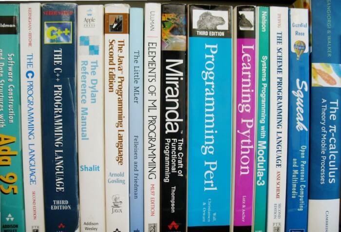 Many programming books kept on a shelf