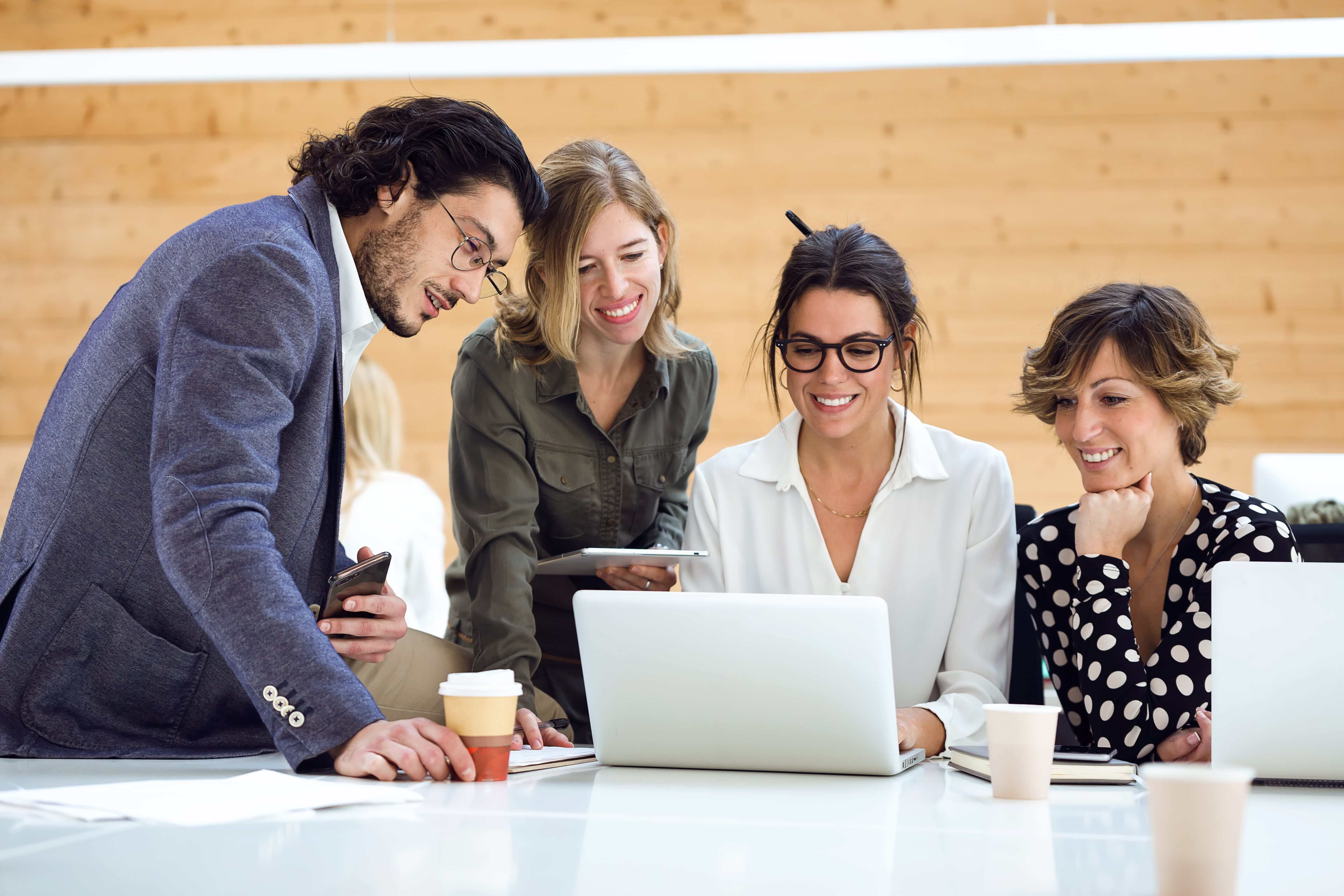 Four adults curiously looking at the laptop