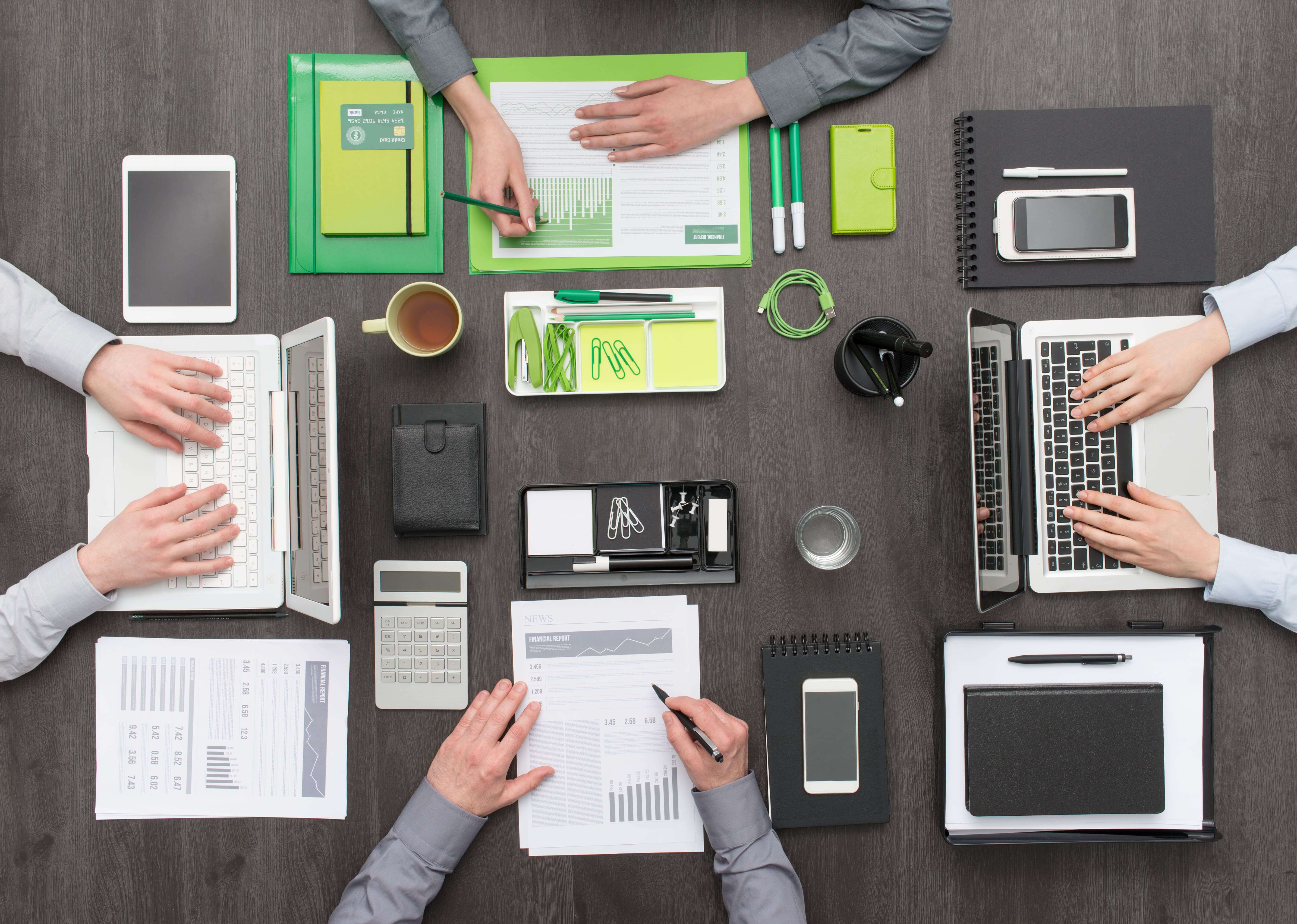 A top view of people working in office on their laptops and documents