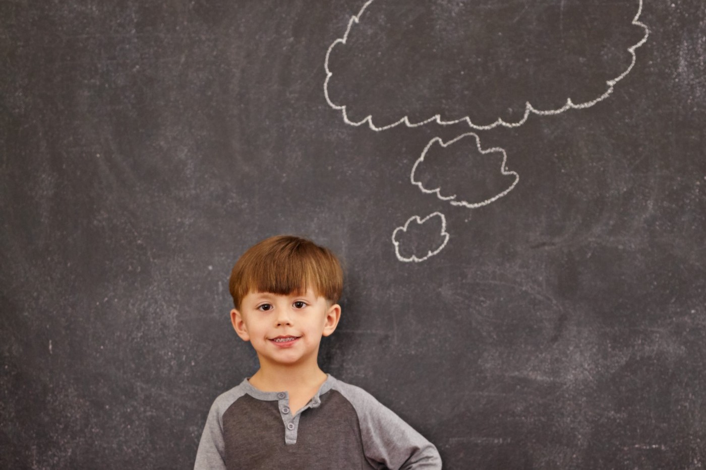 A boy standing in front of blackboard and an imaginary cloud above his head